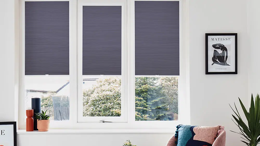 Dark blue pleated Perfect Fit blinds clipped into white uPVC window frames — no drilling required