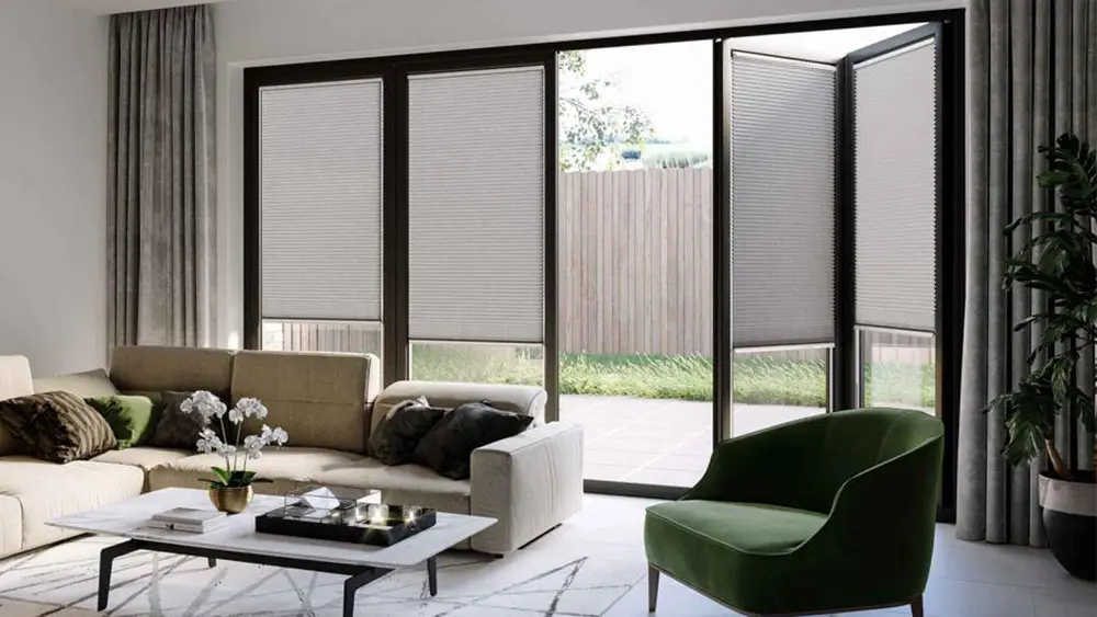 Grey cellular pleated blinds on bi-fold doors in a stylish living room, offering privacy and insulation