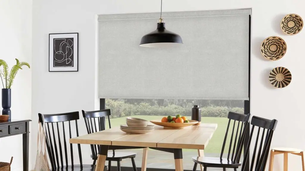 A grey textured roller blind with a neat pelmet cassette in a bright, modern dining room
