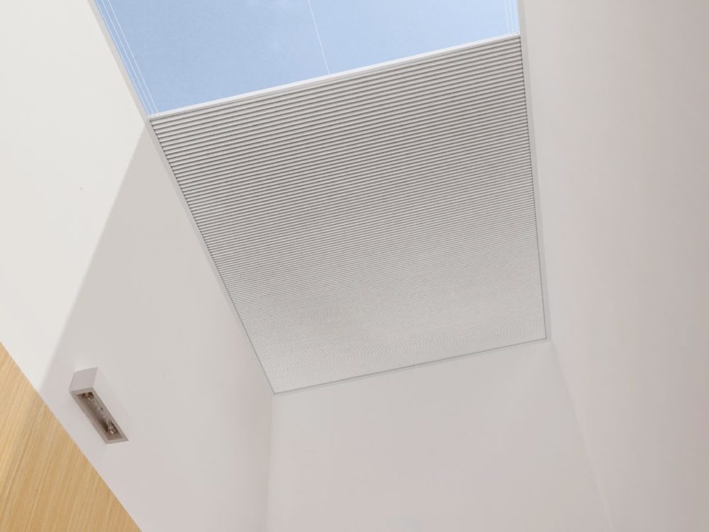 Skylight blind partly closed in a white skylight shaft
